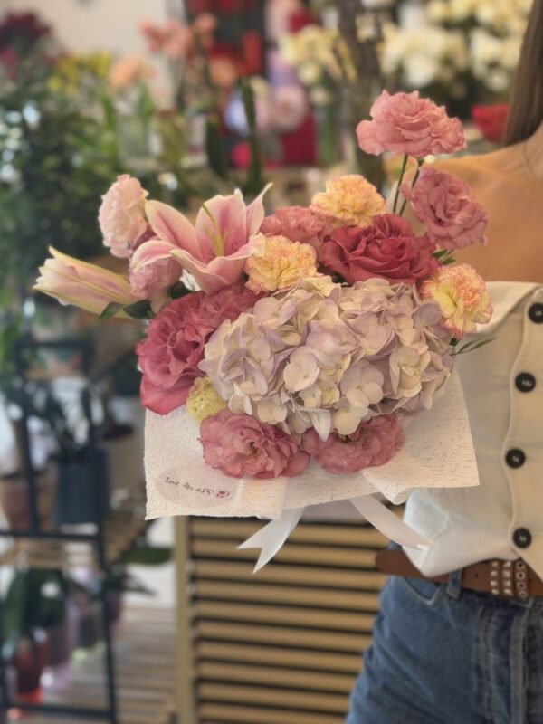 Aranjament floral elegant cu hortensie lila, crini roz și lisianthus, realizat într-o cutie premium albă.