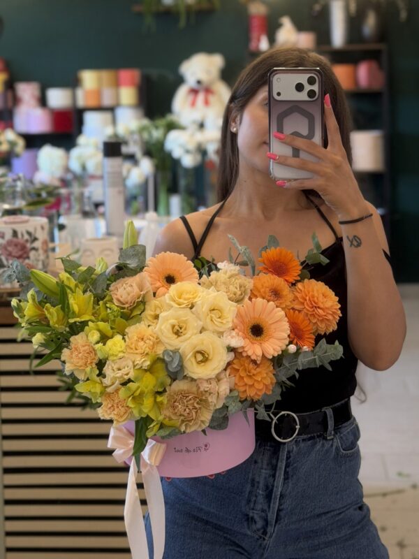 Aranjament floral premium în cutie cu trandafiri crem, gerbera portocalie, alstroemeria galbenă și flori în tonuri calde.