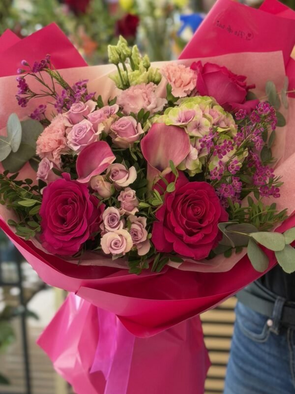 Buchet premium fucsia cu trandafiri, miniroze, cale roz, hortensie și waxflower mov, ambalat elegant.